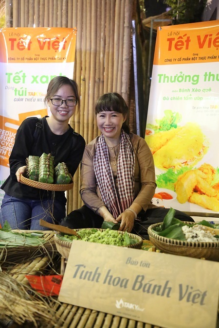 Nghệ nhân bánh Trần Thị Hiền Minh chụp ảnh cùng khách du xuân trải nghiệm gói bánh tét.