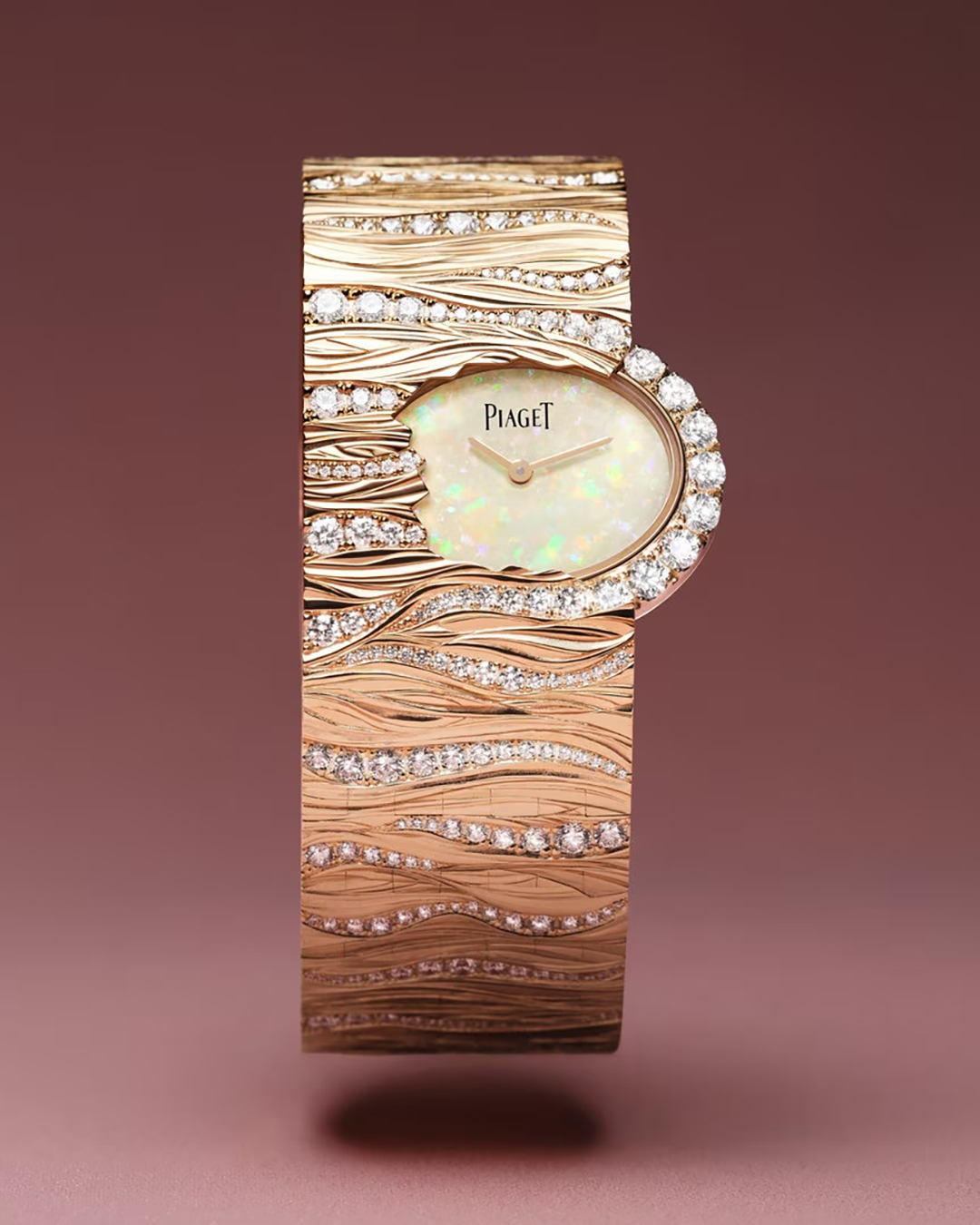 Nhờ sở hữu xưởng vàng độc lập, Piaget thể hiện chuyên môn chế tác qua ba mẫu đồng hồ vòng tay Limelight High Jewelry Cuff mới. Trên chất liệu vàng hồng, mặt vòng đính kim cương khắc hoạ tiết vỏ cây sinh động. Mặt số ngọc mắt mèo trắng như nảy mầm từ những thớ gỗ.